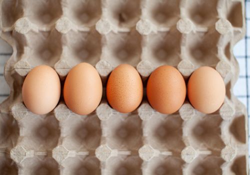 Several brown eggs lie in a row in a large cardboard bag, a chicken egg as a valuable nutritious product, a tray for carrying and storing fragile eggs