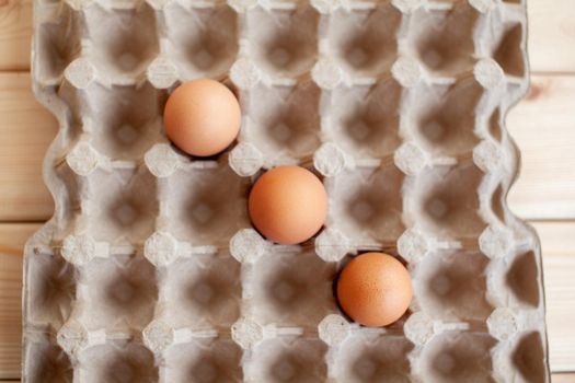 Several brown eggs lie in a row in a large cardboard bag, a chicken egg as a valuable nutritious product, a tray for carrying and storing fragile eggs