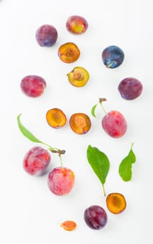 Ripe plums with leaves close up on white background.