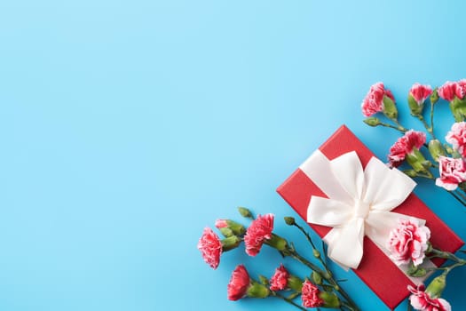 Concept of Mother's day holiday greeting gift design with carnation bouquet on bright blue table background