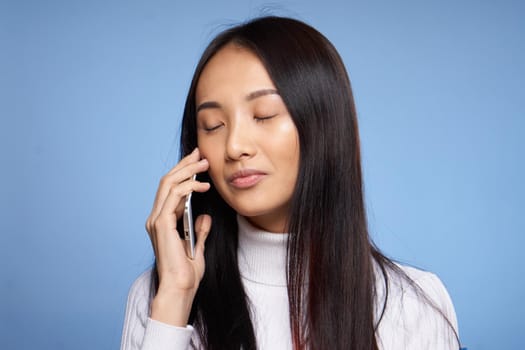 Asian woman limbs talking on the phone on blue background studio. High quality photo
