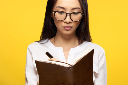 asian woman with notebook in hand learning student yellow background. High quality photo