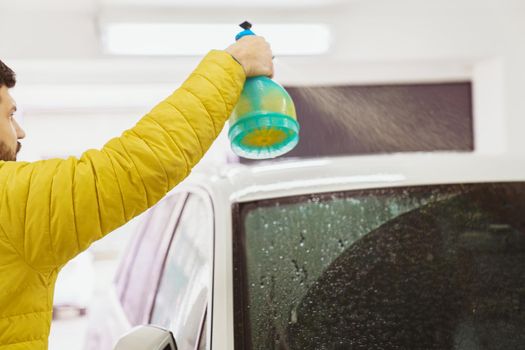 man cleans the car body with a sprayer. auto care.