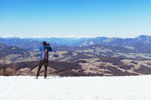 hiker on the top of the mountain takes pictures on his smartphone.