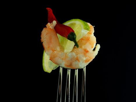 Snack on a fork. Texture of boiled shrimp meat on a fork with a slice of lime and red pepper. High quality photo