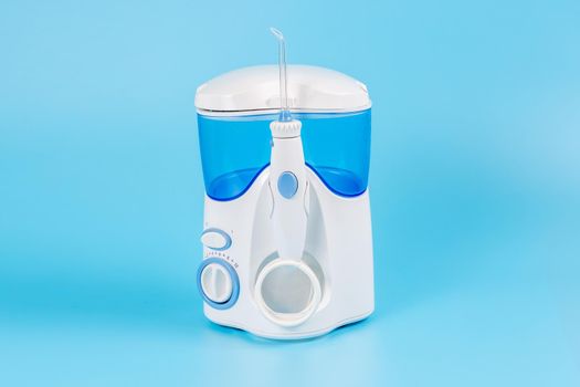 Electronic Tooth Irrigator for personal home usage on blue background. The concept of proper oral care, caries hygiene.