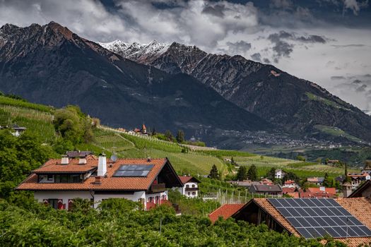 Panorama of solar batteries on roof top, green slopes of the mountains of Italy, Trentino, huge clouds over a valley, green meadows, a clear energy, energy of the sun, Solar panels