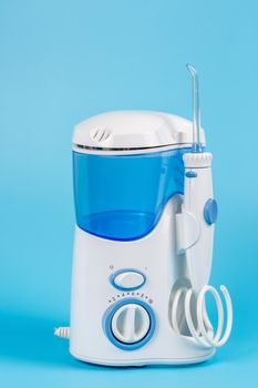 Electronic Tooth Irrigator for personal home usage on blue background. The concept of proper oral care, caries hygiene.