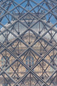 Astonishing view of the top of Louvre Museum from inside glass pyramid. Famous palace with classic architecture behind glass and metal structure in Paris, France. French landmarks