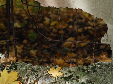 A broken concrete fence. A hole from a shell in a concrete fence with wire.