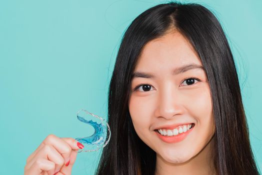 Portrait young Asian beautiful woman smiling holding silicone orthodontic retainers for teeth, Teeth retaining tools after removable braces, Orthodontics dental healthy care concept 