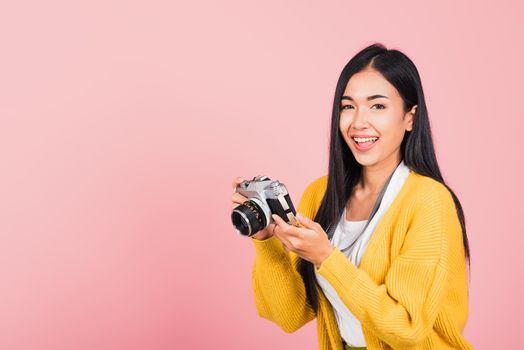 Attractive energetic happy Asian portrait beautiful cute young woman teen excited smiling holding vintage photo camera, studio shot isolated on pink background, traveler female photographer