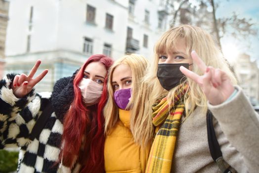 portrait of a group of girls with protected wearing masks, making the Two Finger Peace Sign Hand Gesture . Concept of happiness and security at the quarantine time