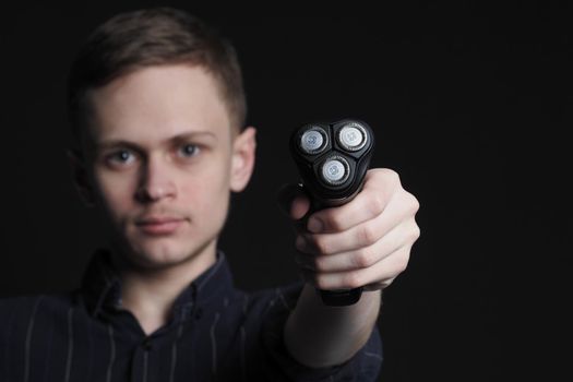 A young man holds an electric razor with floating blades in his hand. High quality photo