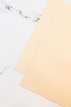 Beige A4 papers on white marble background as office stationery flatlay, luxury branding flat lay and brand identity design for mockups