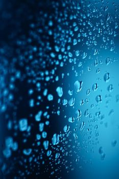 Liquid water drops on glass surface, abstract backdrop and science background concept