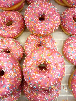 The doughnuts are sweet in a sugar pink glaze, a bakery showcase. High quality photo