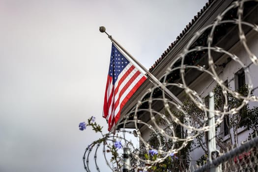 Concept of political isolationism and economic slowdown in the United States of America. Flag behind barbed wire.