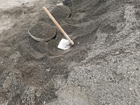 Fawda and ghamela, spade and tasla lying on heap of gravel on a construction site.A