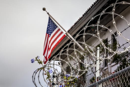 Concept of political isolationism and economic slowdown in the United States of America. Flag behind barbed wire.