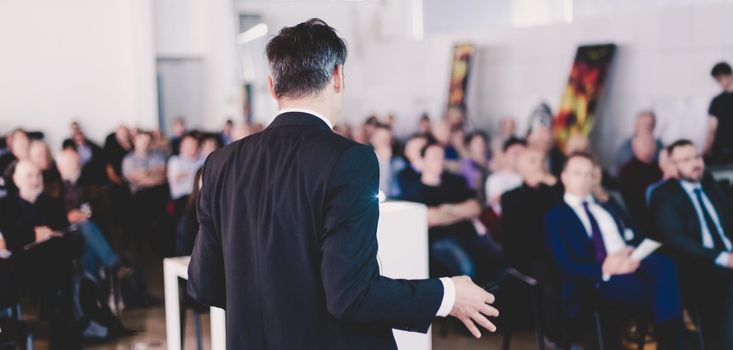 Speaker at Business Conference with Public Presentations. Audience at the conference hall. Business and Entrepreneurship concept. Background blur. Shallow depth of field.