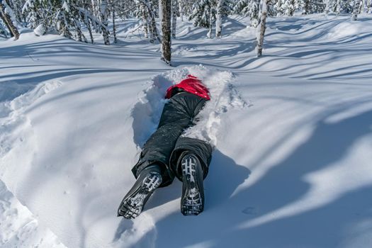 A skier sleeping in a snowdrift, covered with snow, lies among the forest