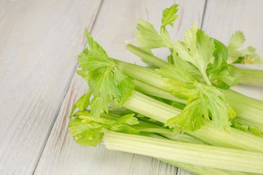 Bunch of fresh celery stalk with leaves on a wooden background.