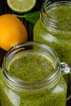 Healthy green smoothie with spinach, mango, orange,lime, apple,citrone in glass jars.