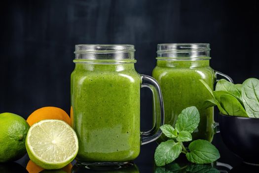 Healthy green smoothie with spinach, mango, orange,lime, apple,citrone in glass jars.