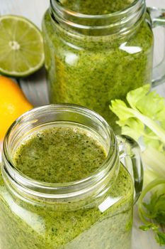 Healthy green smoothie with spinach, mango, orange,lime, apple,citrone in glass jars.