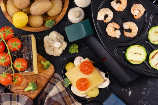 Delicious traditional Swiss melted raclette cheese on chopped boiled potatoes with vegetables.