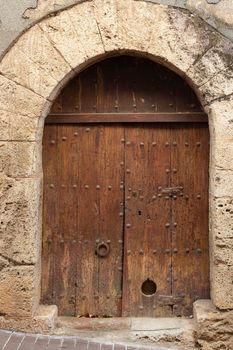 Old wooden door with stone arch, in Girona, Catalonia, Spain