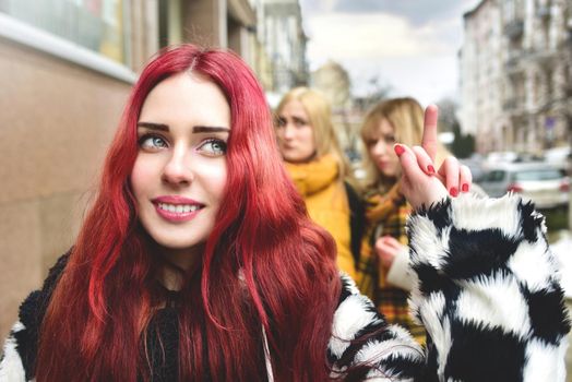 Self-confident teenage girl ignores jealous people who spread gossip behind her back. stop bullying. social problems. a girl shows her middle finger to her detractors.