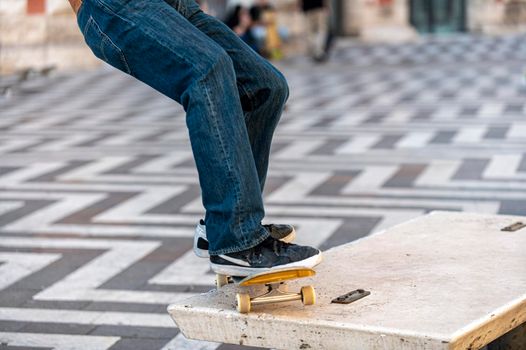 detail of a boy doing stunts with his skateboard in the city on a bench