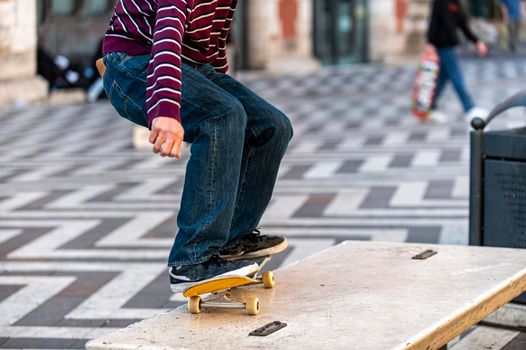 detail of a boy doing stunts with his skateboard in the city on a bench