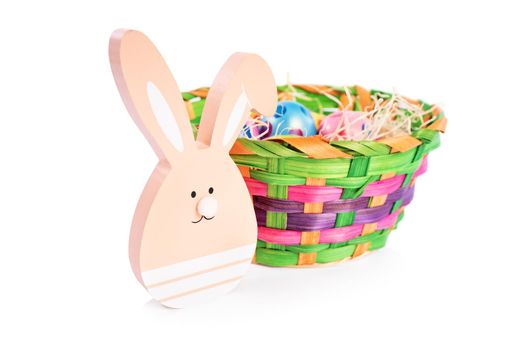 Close up of Easter bunny and a basket filled with colourful Easter eggs with polka dots, isolated on white background. Fun and colorful Easter celebration concept.