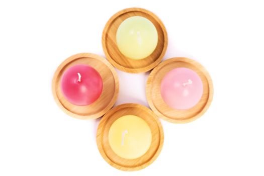 Top view of egg shaped candles in pastel colors on wooden saucers, isolated on white background. Fun and colorful Easter celebration concept. Easter decoration concept.