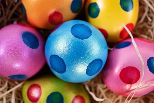 Top close up view of colourful Easter eggs with polka dots in a basket, isolated on white background. Easter celebration concept.