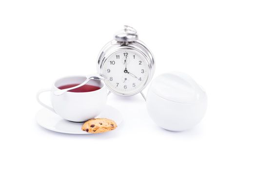 Chick white cup of tea with chocolate chip cookies and an alarm clock, isolated on white background.