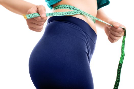 Close up of a fit young girl measuring her waist with a measuring tape, isolated on white background.