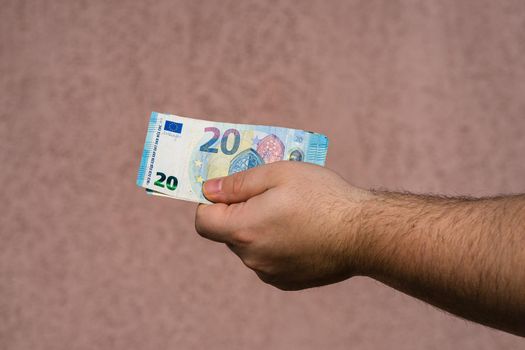 Hand holding showing euro money and giving or receiving money like tips, salary. 20 EURO banknotes EUR currency isolated. Concept of rich business people, saving or spending money.