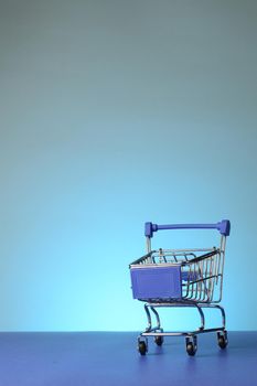 A miniature blue shopping cart over a blue gradient background.