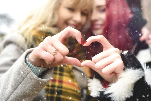 Lesbian couple making heart with hands, open relationship in love. love concept. friendship concept. snowy effect