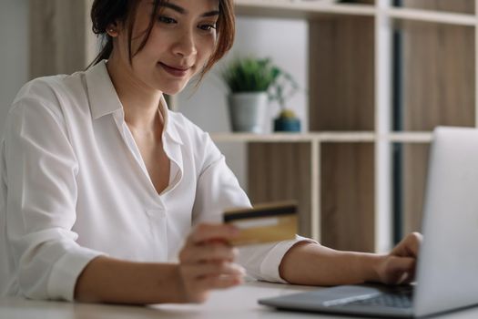 Happy woman using laptop computer and credit card for shopping online at home