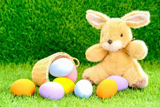 Easter bunny toy and Easter eggs in basket on green grass