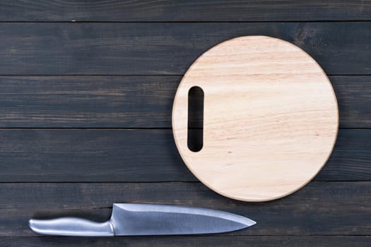 Close up kitchen knife and wooden round empty cutting board on a wooden table