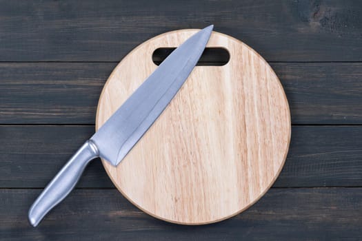 Close up kitchen knife and wooden round empty cutting board on a wooden table