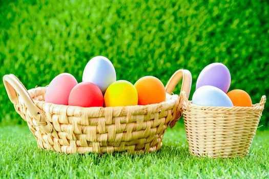 Colorful easter eggs in the basket on green grass background with copy space