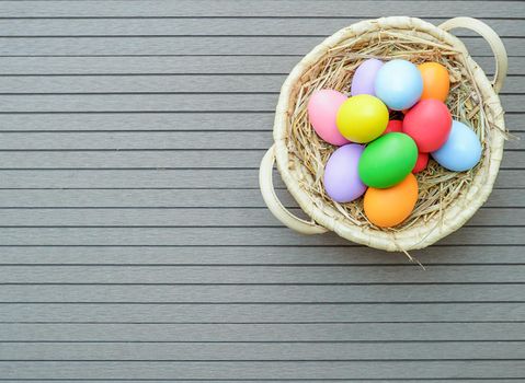 Colorful easter eggs in the basket on wood background with space