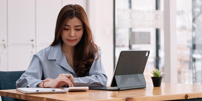 Business accounting concept, Businesswoman using calculator with computer laptop, budget tax and loan paper at home.